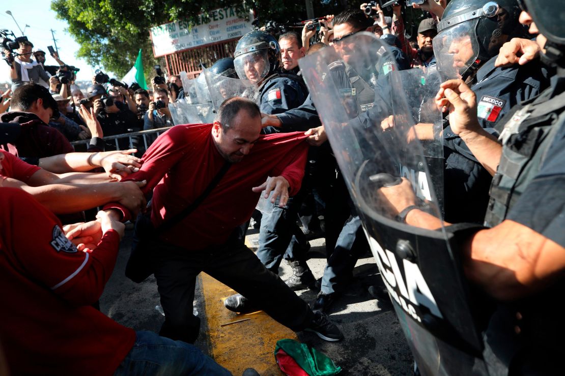 Demonstrators clash with police outside a migrant shelter as they protest the presence of thousands of Central American migrants in Tijuana on Sunday.