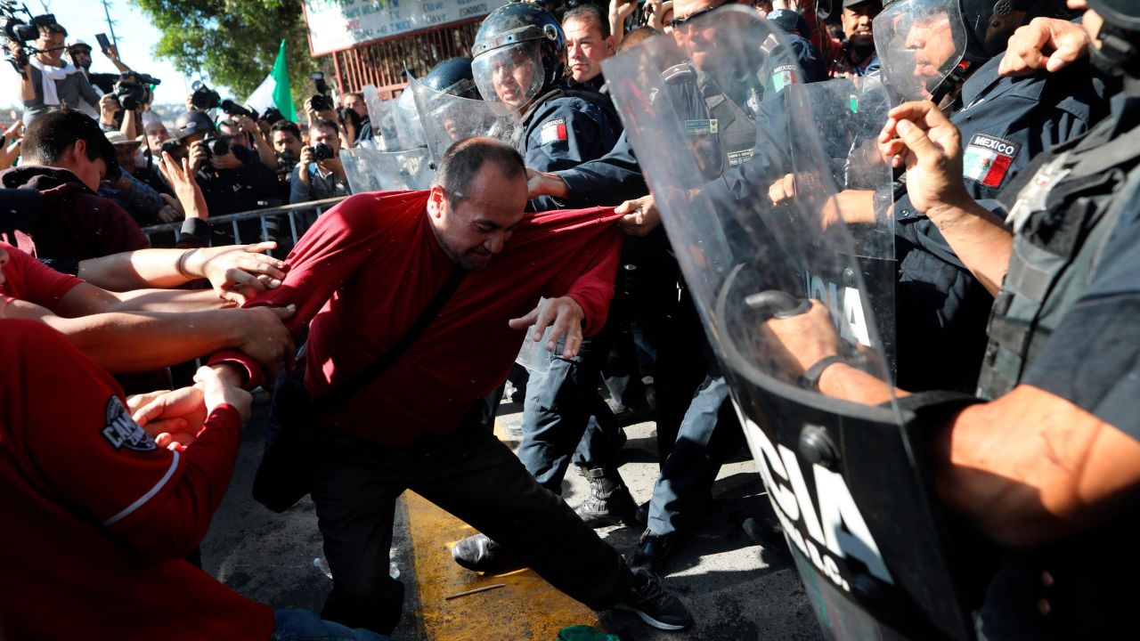 Demonstrators clash with police outside a migrant shelter as they protest the presence of thousands of Central American migrants in Tijuana on Sunday.