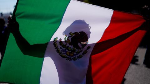 A demonstrator holds a Mexican flag outside a migrant shelter to protest the presence of thousands of Central American migrants in Tijuana, Mexico, on Sunday. 