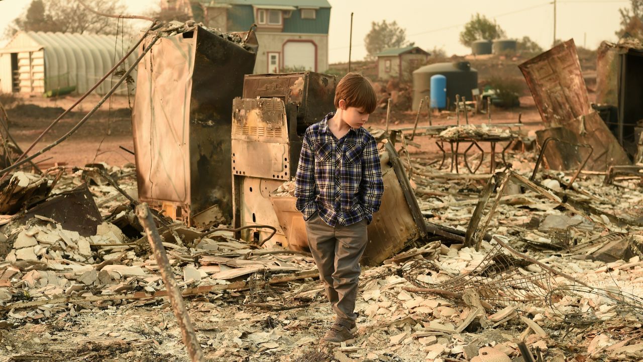 Jacob Saylors, 11, walks through the remains of his home Sunday in Paradise, California.