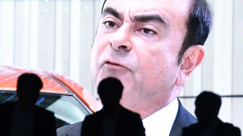 TOPSHOT - Men walk past a screen showing a news programme featuring Nissan chairman Carlos Ghosn in Tokyo on November 20, 2018. - Nissan and Mitsubishi shares plunged on November 20, as the automakers prepared to oust chairman Carlos Ghosn a day after he was arrested for alleged financial misconduct. (Photo by Toshifumi KITAMURA / AFP)        (Photo credit should read TOSHIFUMI KITAMURA/AFP/Getty Images)
