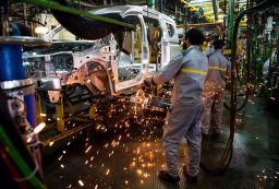 Factory employees work on a car assembly line at Renault-Nissan.