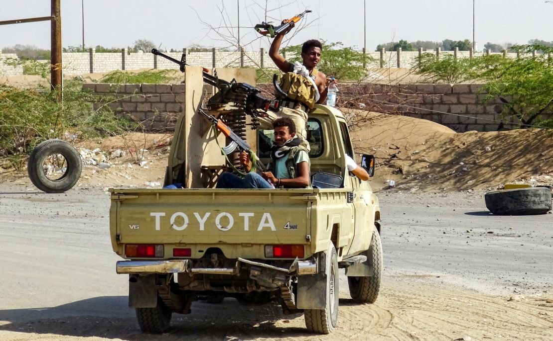 Pro-government forces cheer in the back of a pickup mounted with a machine gun outside Hodeidah.