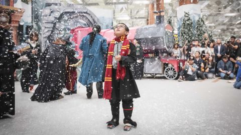 A young fan enthralled by the snow at a wintry Hogsmeade Village-inspired setup at Terminal 3 Departure Hall