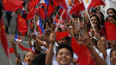 Schoolchildren wave the  flags of the Philippines and China as they line up November 20 along the route of China's President Xi Jinping's motorcade in Manila.