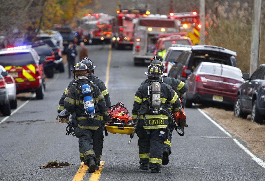 Firefighters carry a stretcher to the scene of a fatal fire on November 20, 2018, in Colts Neck, New Jersey.