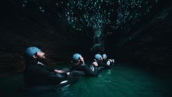Visitors float through an underground river as glowworms light the Waitomo Cave ceiling.