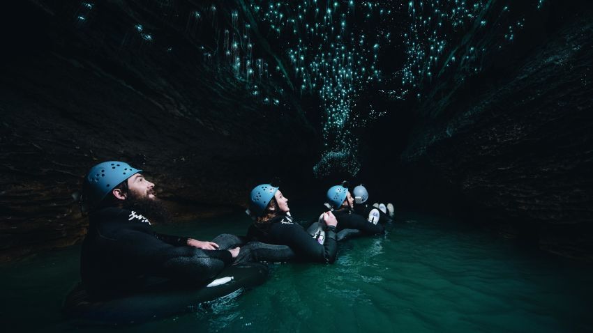 Visitors float through an underground river as glowworms light the Waitomo Cave ceiling. 