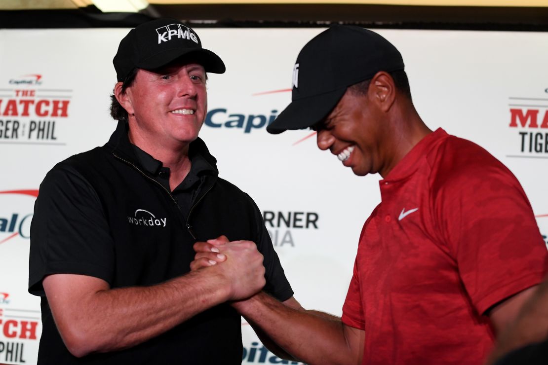 Phil Mickelson and Tiger Woods shake hands during a press conference.