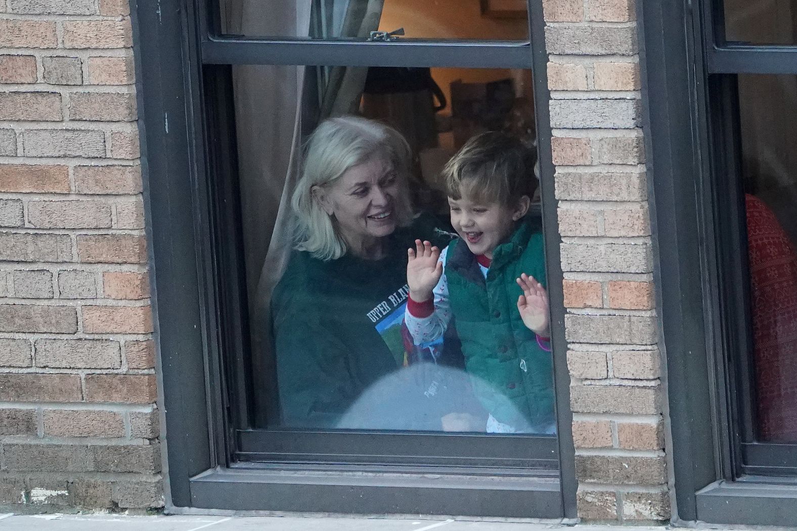 A child watches the parade from a window on Sixth Avenue.