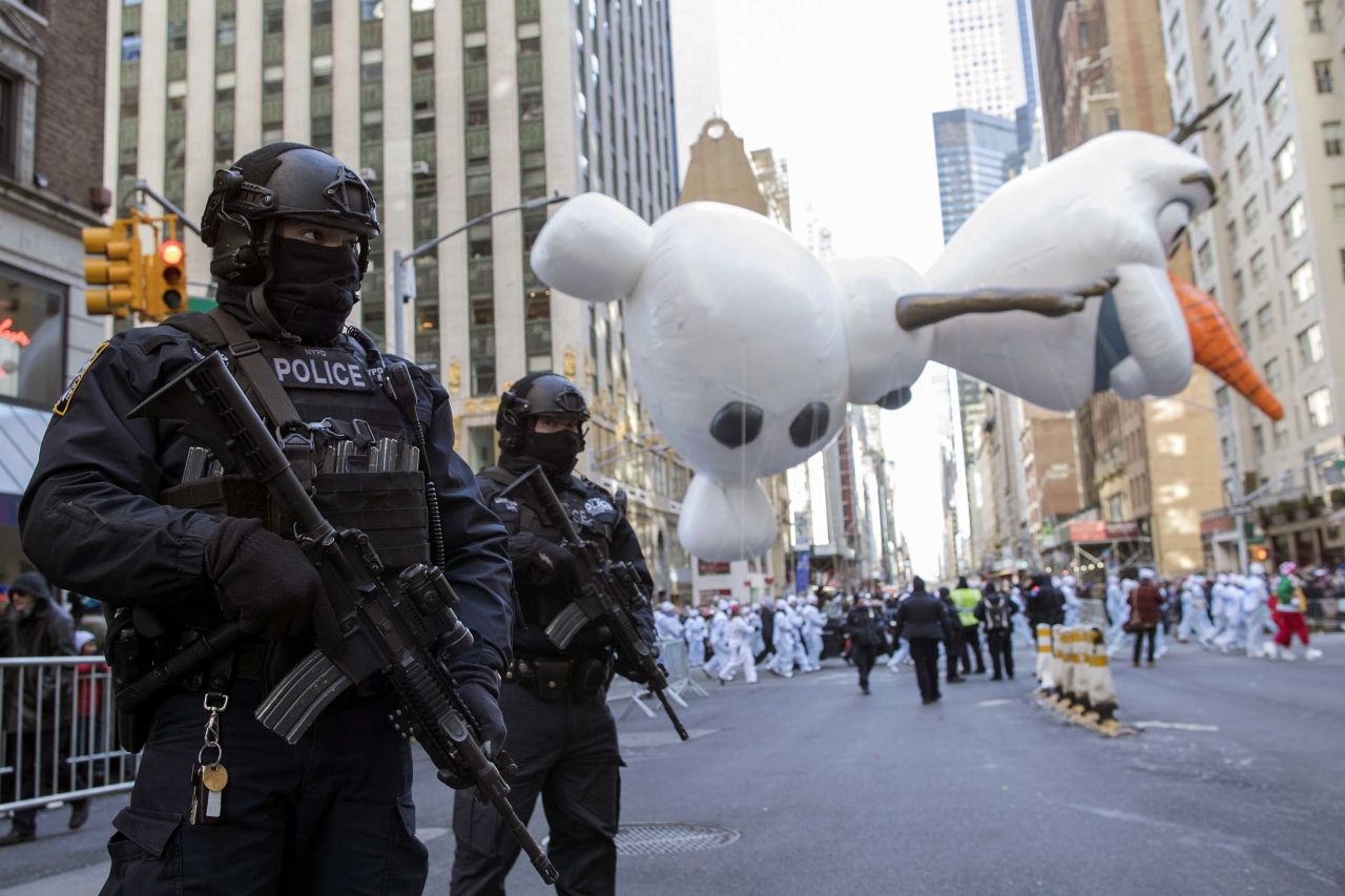 Police officers stand guard as an Olaf balloon floats down Sixth Avenue.