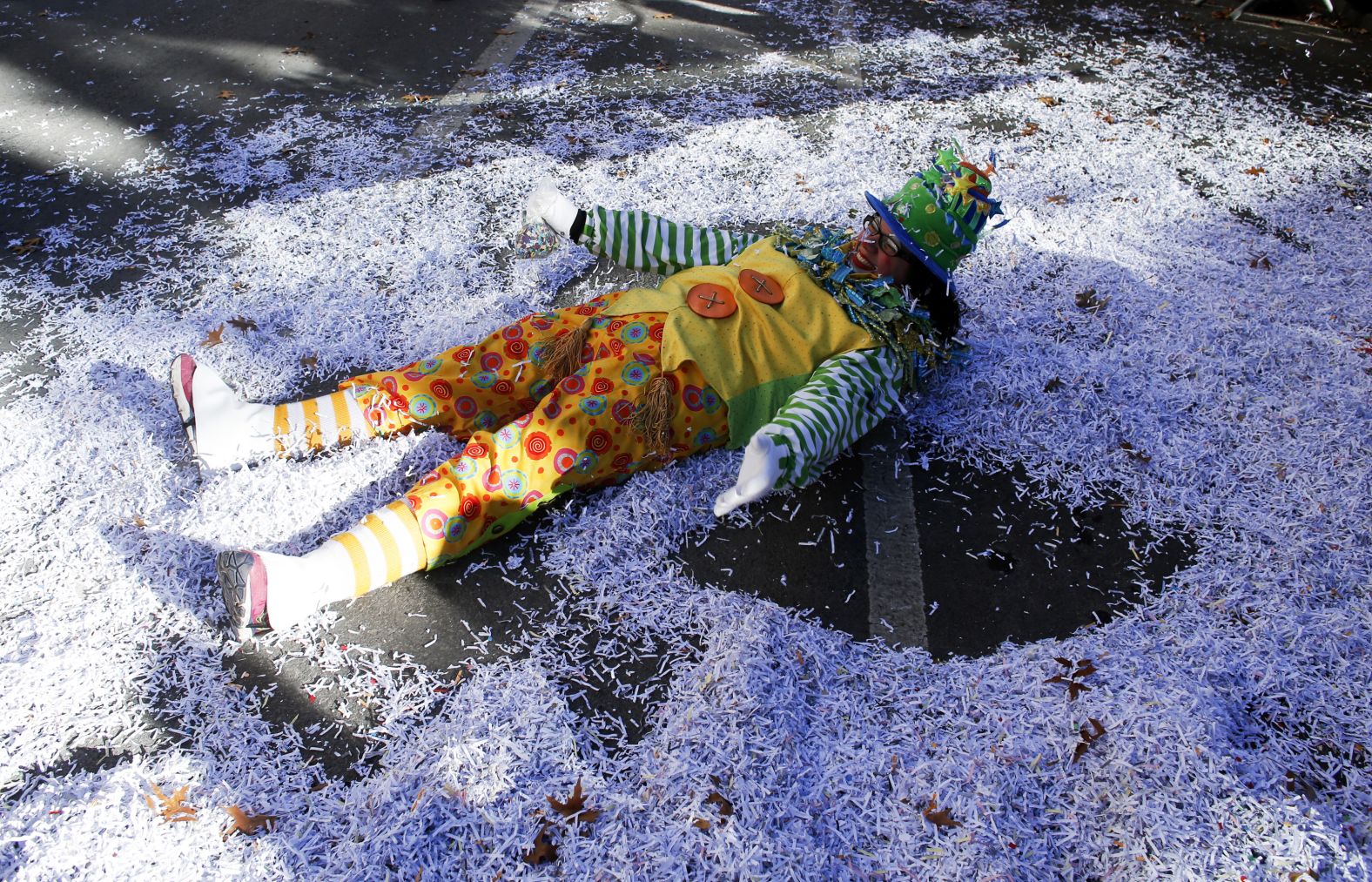 A parade participant makes a snow angel from confetti.