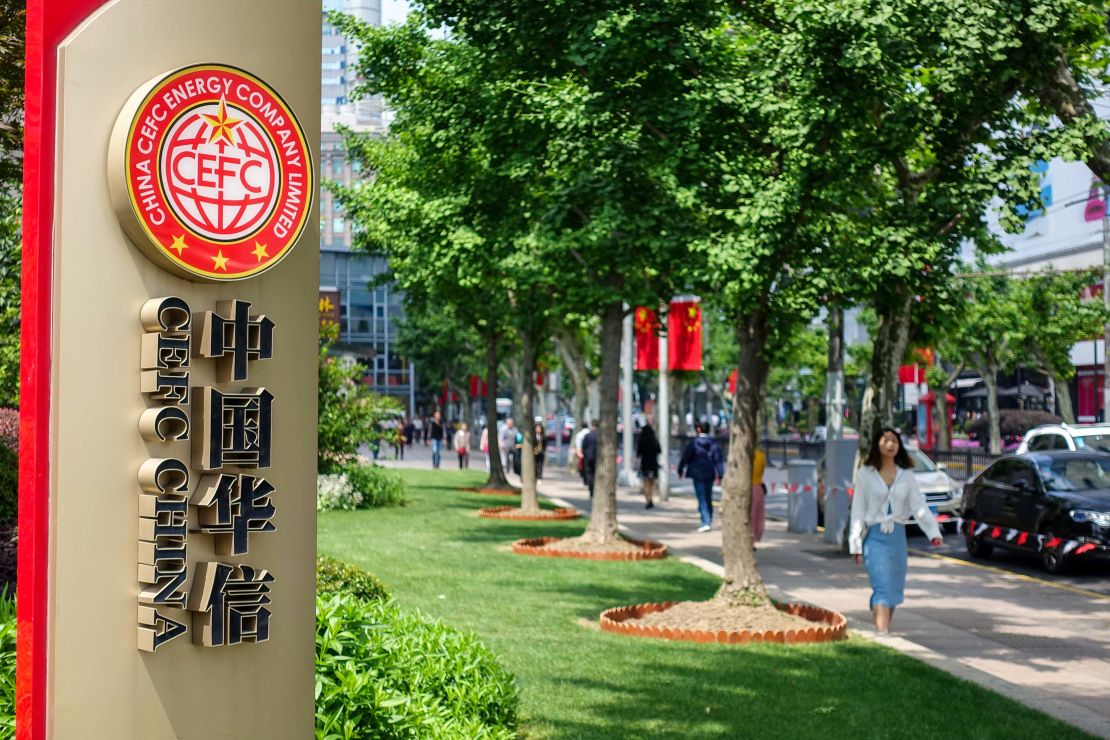 Pedestrians walk past a signboard of China CEFC Energy in Shanghai, China, in May 2018.
