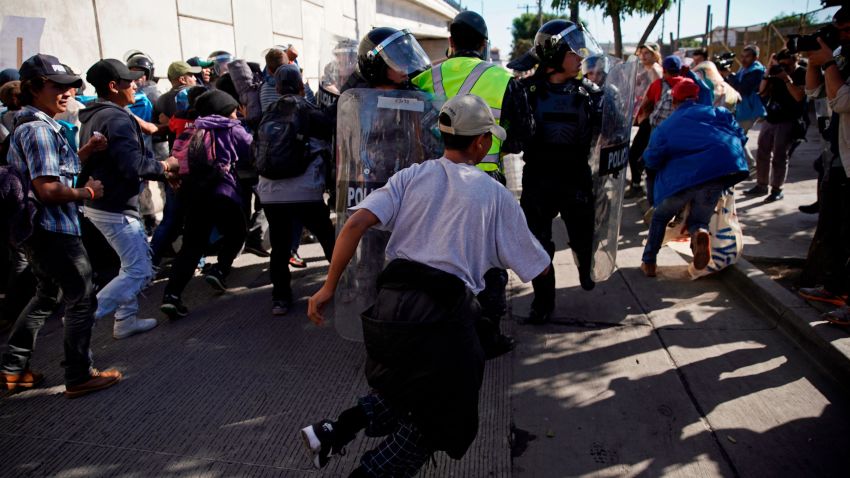 Migrants break past a line of police as they run toward the Chaparral border crossing in Tijuana, Mexico, Sunday, Nov. 25, 2018, near the San Ysidro entry point into the U.S. More than 5,000 migrants are camped in and around a sports complex in Tijuana after making their way through Mexico in recent weeks via caravan.  (AP Photo/Ramon Espinosa)