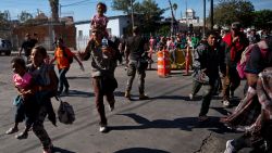 Migrants run toward the U.S. after breaking past a line of Mexican police at the Chaparral border crossing in Tijuana, Mexico, Sunday, November 25 near the San Ysidro, California entry point. More than 5,000 migrants are camped in and around a sports complex in Tijuana after making their way through Mexico in recent weeks.
