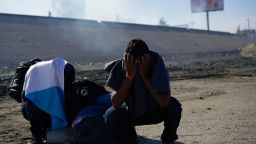 Three Honduran migrants huddle in the riverbank amid tear gas fired by U.S. agents on the Mexico-U.S. border after they and a group of migrants got past Mexican police at the Chaparral border crossing in Tijuana, Mexico, Sunday, Nov. 25, 2018. The mayor of Tijuana has declared a humanitarian crisis in his border city and says that he has asked the United Nations for aid to deal with the approximately 5,000 Central American migrants who have arrived in the city. 