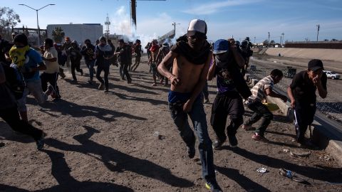 Migrants run along the Tijuana River near the US-Mexico border after US agents threw tear gas to disperse them.