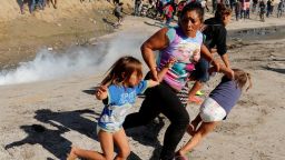 A migrant family from Honduras, part of a caravan of thousands traveling from Central America en route to the US, runs from tear gas released by US border patrol near the fence between Mexico and the United States in Tijuana, Mexico, November 25.