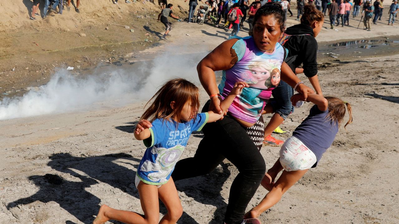 A migrant family runs from tear gas released by US border patrol agents near the fence between Tijuana, Mexico, and San Diego.