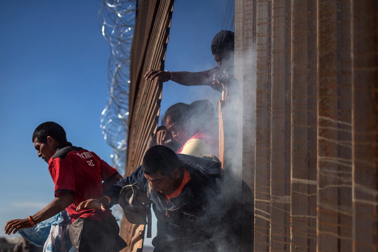 Migrants return to Mexico after tear gas was deployed.