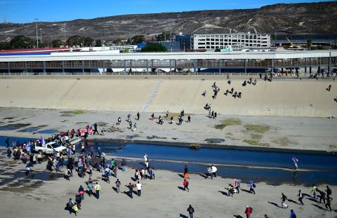 Migrants cross the riverbed of the Tijuana River as they try to get to the port of entry.