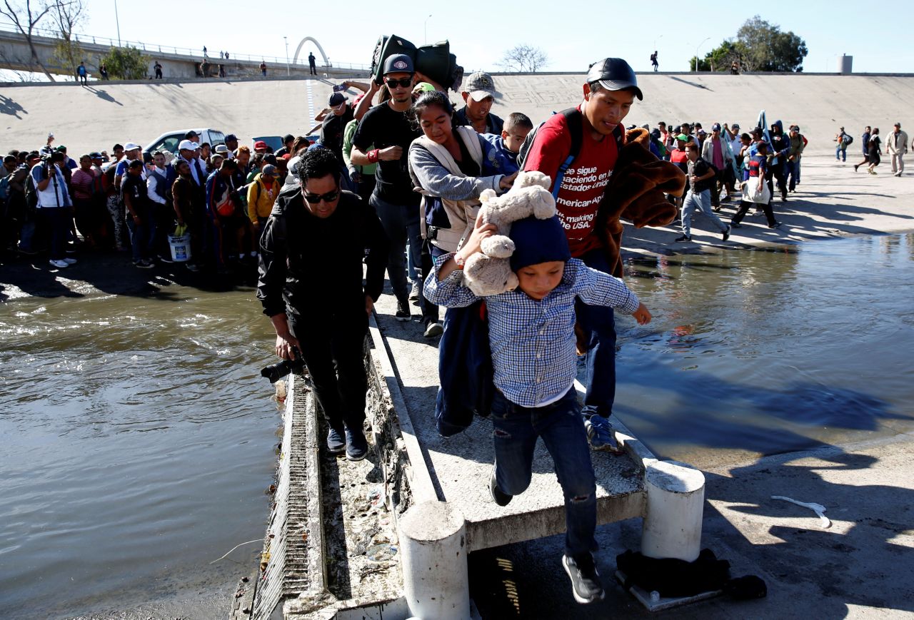 Migrants cross the Tijuana River to reach the border fence.