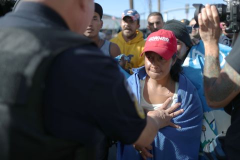 A migrant is pushed back as she attempts to break through a line of Mexican police to reach the border wall.