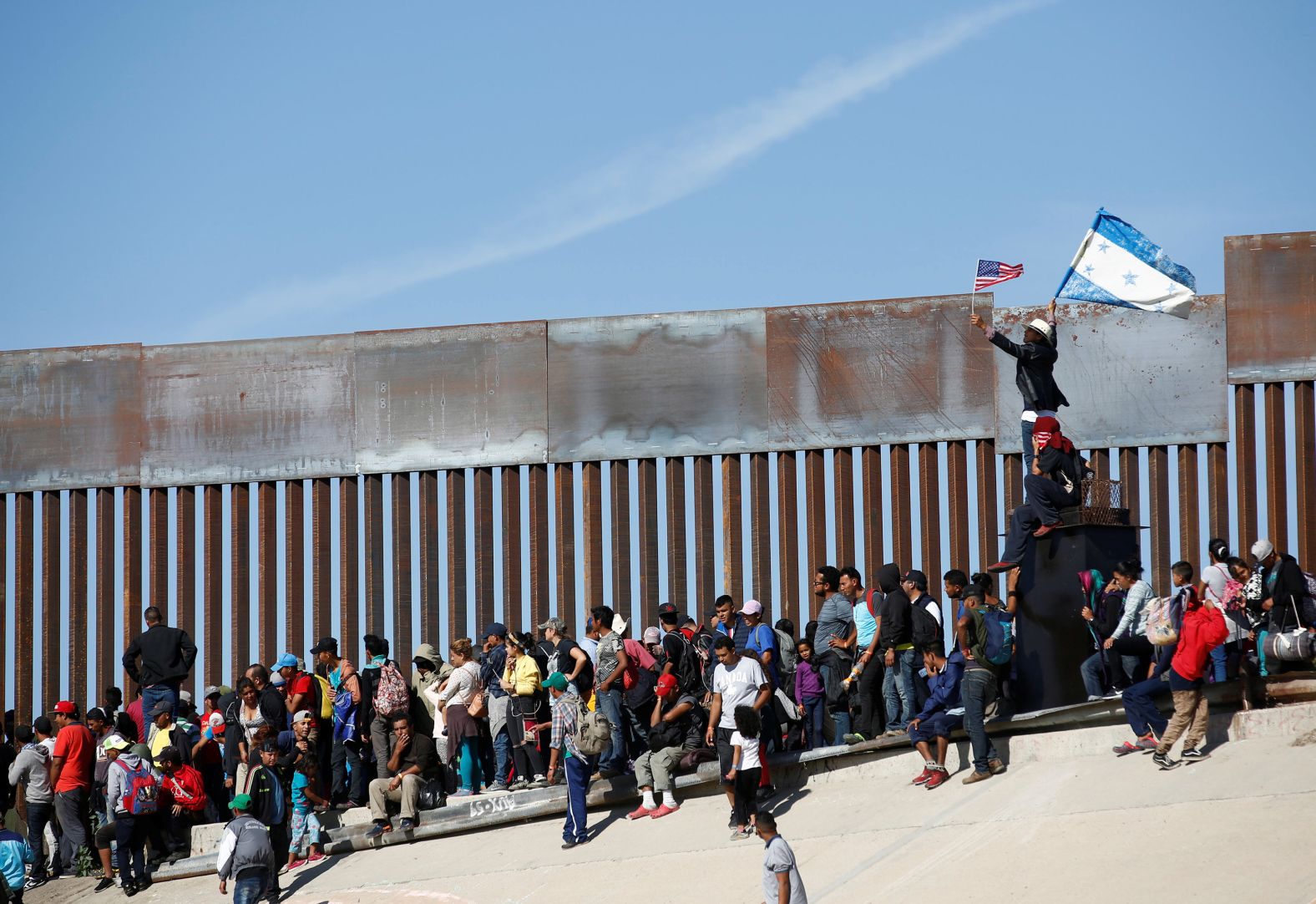 A migrant holds US and Honduran flags in front of the border fence in Tijuana, Mexico, on November 25. Some migrants have told CNN they're fleeing violence, persecution or crushing poverty in their homelands and are<a href="index.php?page=&url=https%3A%2F%2Fwww.cnn.com%2F2018%2F11%2F26%2Famericas%2Fmigrant-caravan-profiles%2Findex.html" target="_blank"> willing to work any job</a> in the US.