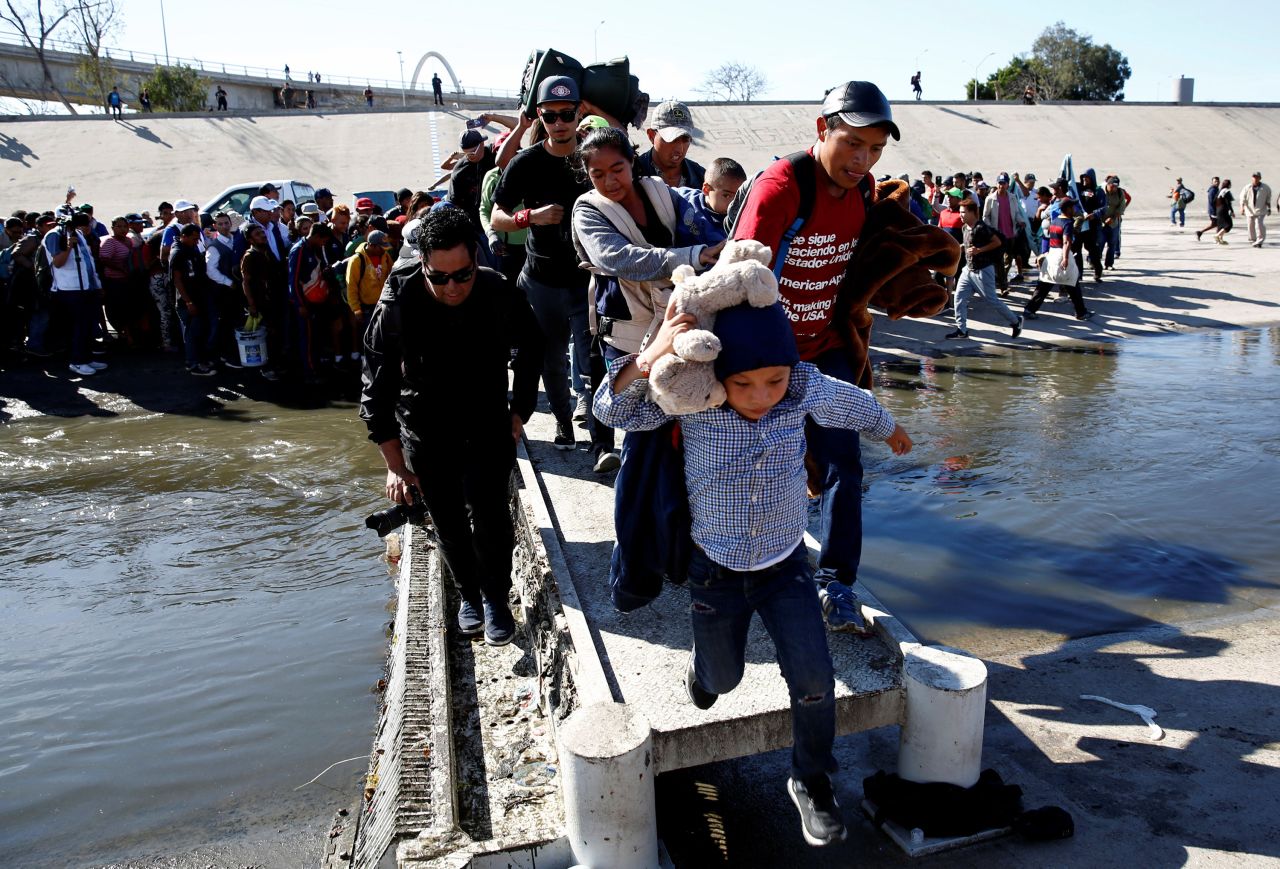 Migrants cross the Tijuana River to reach the border fence Sunday on November 25. On the US side, 69 people were arrested after entering illegally, US Customs and Border Protection Commissioner Kevin McAleenan said.