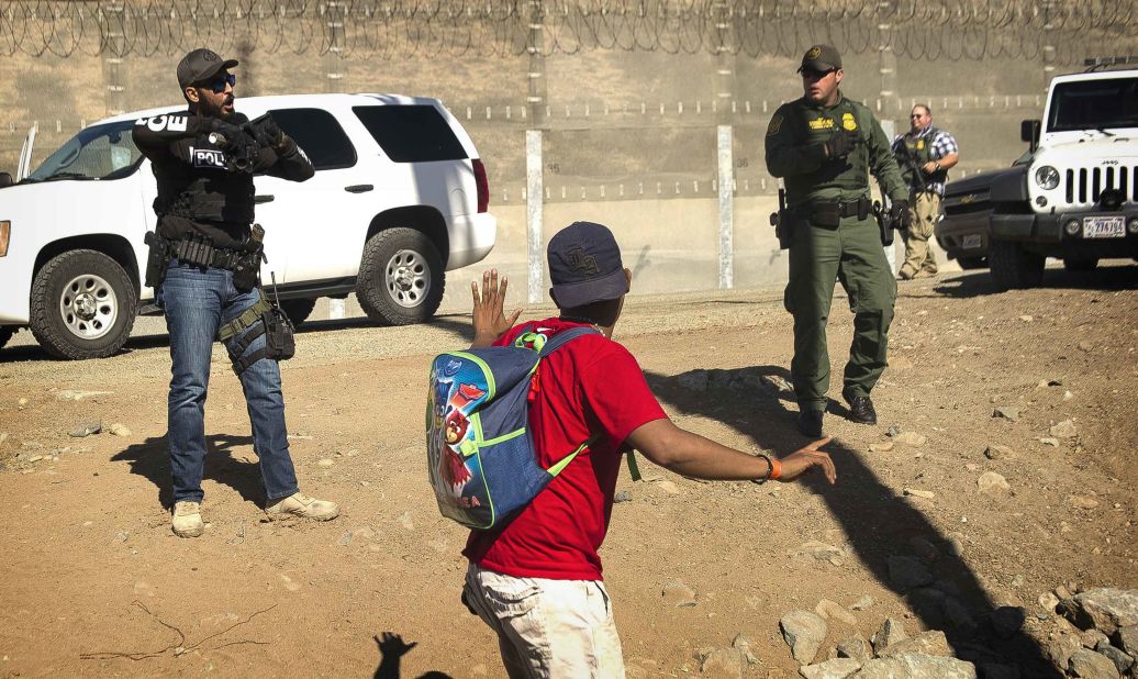 A migrant is stopped by US agents who order him to go back to the Mexican side of the border.