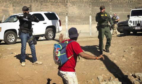 A migrant is stopped by US agents who order him to go back to the Mexican side of the border.