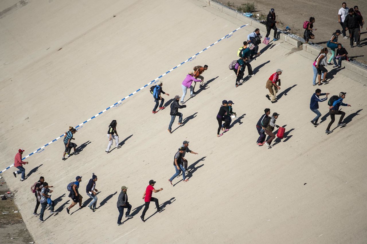 A group of migrants crosses the riverbed of the Tijuana River in an attempt to get to the port of entry.