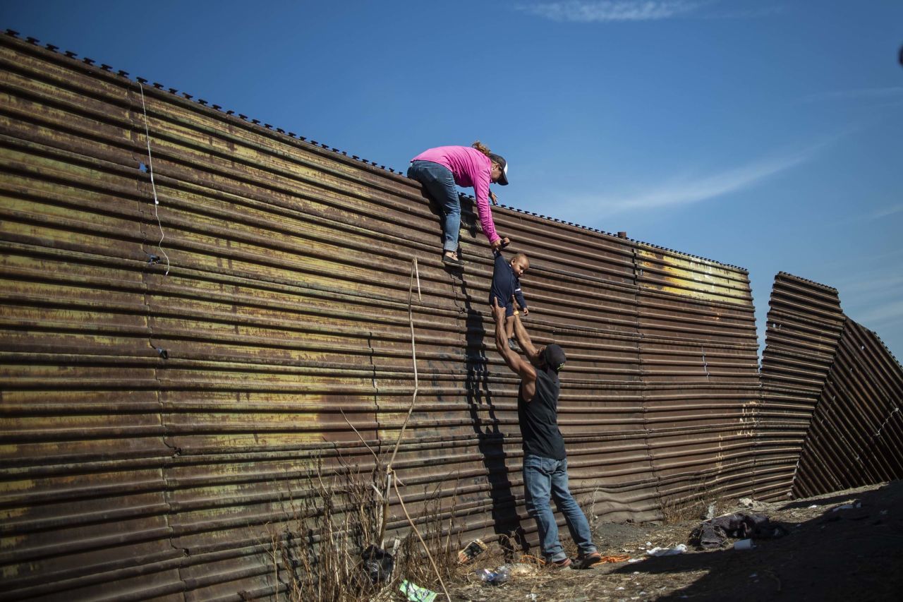 A group of migrants climbs the border fence between Mexico and the United States.