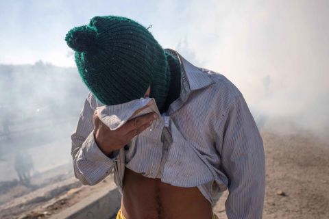A migrant covers his face after being affected by tear gas.