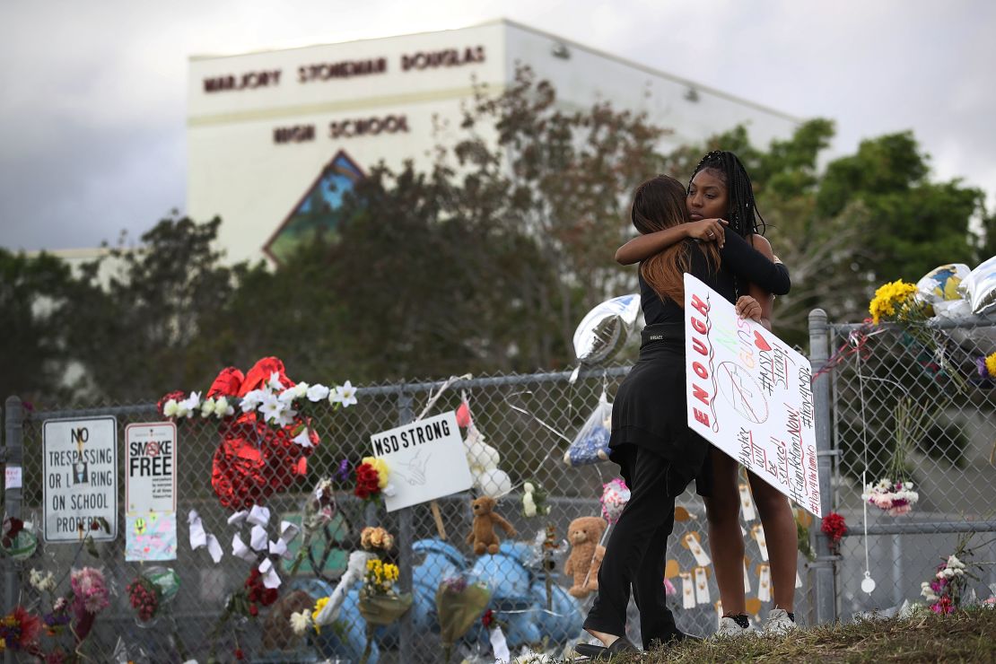 Tyra Heman, right, a senior at Marjory Stoneman Douglas High School, is hugged by Rachael Buto in front of the school where 17 people were killed on February 14 in Parkland, Florida.