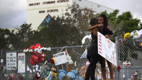 Tyra Heman, right, a senior at Marjory Stoneman Douglas High School, is hugged by Rachael Buto in front of the school where 17 people were killed on February 14 in Parkland, Florida.