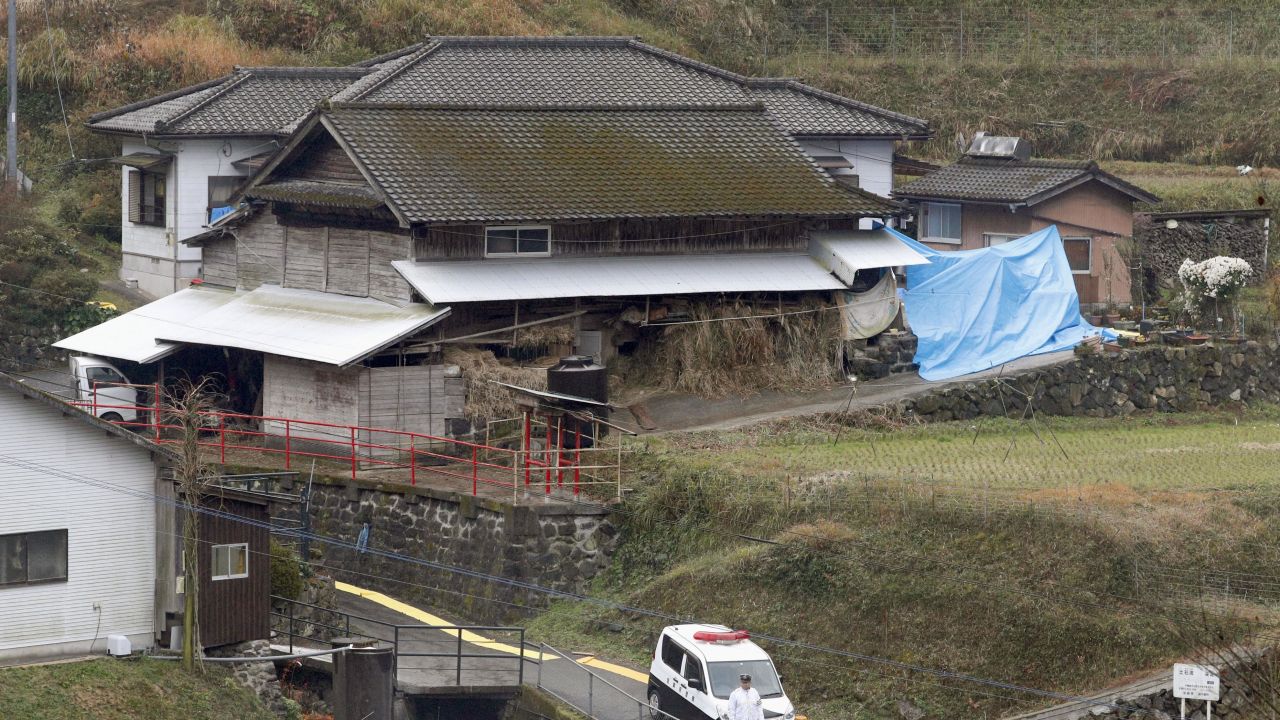 A police officer cordons off a path leading to the house in Takachiho, southwestern Japan, where six bodies were found.
