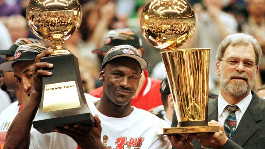 Michael Jordan, seen here with Phil Jackson, raises his NBA Finals MVP trophy following a last-second shot to secure a third straight title for the Chicago Bulls.