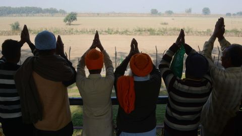 Indian Sikh devotees offers prayers as they look towards the Kartarpur temple, which is situated in Pakistan, from the Indian side on the outskirts of Amritsar, on November 25, 2018. 