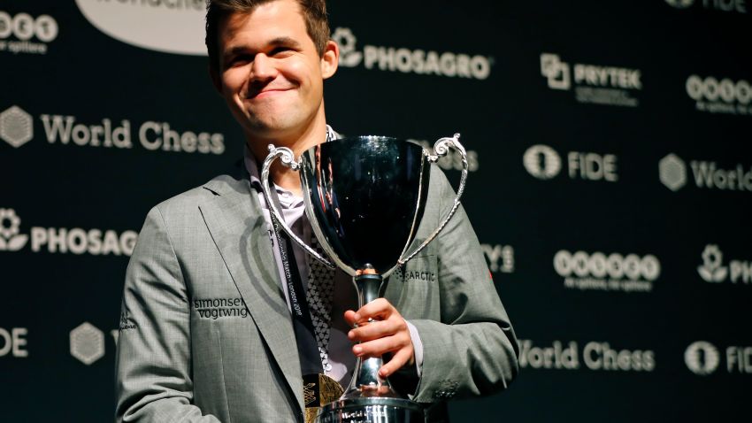 World chess champion Norway's Magnus Carlsen poses with the FIDE world chess championship trophy after beating challenger, US player Fabiano Caruana (not pictured) in the tie-break matches of the 2018 World Chess Championship in London on November 28, 2018. - Three-time defending chess champion Magnus Carlsen on Wednesday successfully defended his world title after demolishing US hopeful Fabiano Caruana in a winner-take-all finale. (Photo by Tolga AKMEN / AFP)        (Photo credit should read TOLGA AKMEN/AFP/Getty Images)