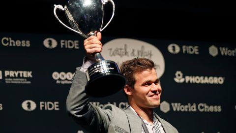 Carlsen poses with the FIDE world chess championship trophy 