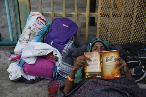Luis Rene Reyes Garcia, a 28-year-old from Guatemala, reads a donated Bible as he rests on the street outside of the shelter.