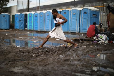 A man steps across mud after taking a shower at the shelter.