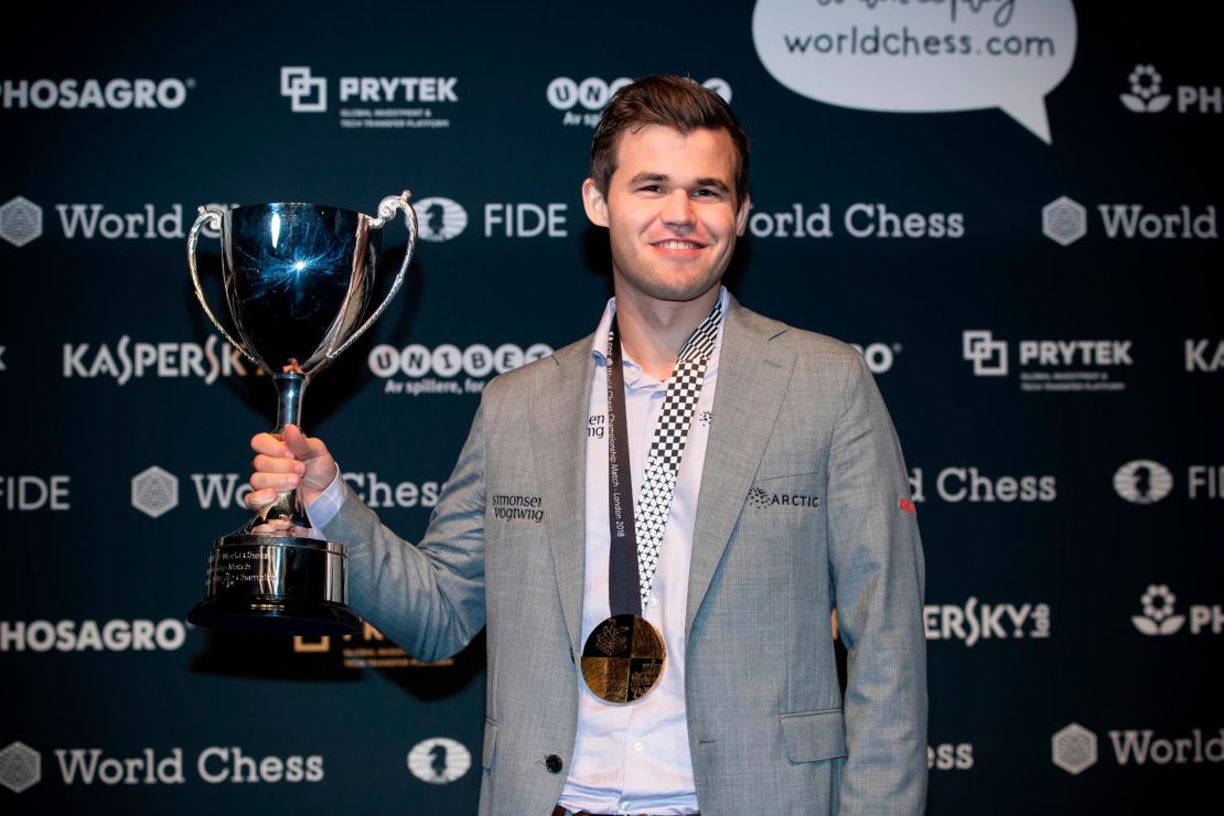 Carlsen holds his trophy up after beating Fabiano Caruana to regain his World Chess Championship title on November 28, 2018 in London.