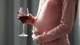 Pregnant woman with glass of red wine in hand 