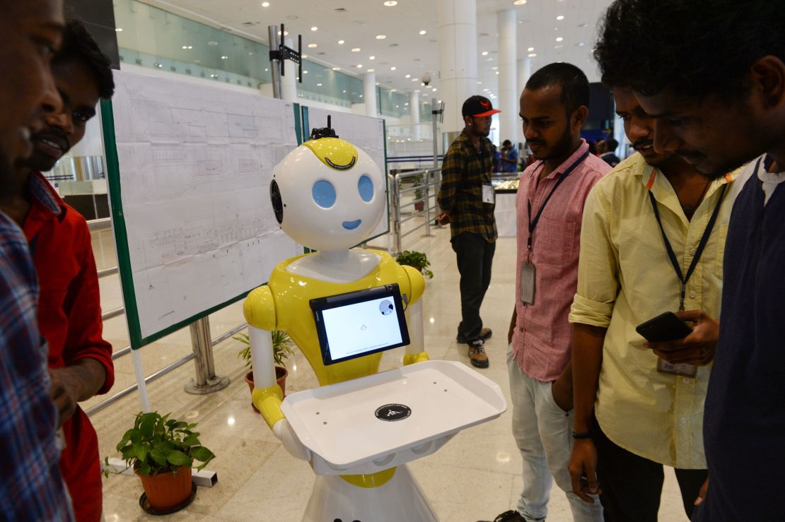 Staff check out one of the humanoid robots in the arrival hall of Chennai International Airport.