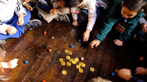 NEW YORK - DECEMBER 4: PS 1 second grade students play with dreidels and chocolate gold coins after lighting the menorah December 4, 2007 at the Eldridge St. Synagogue in New York City. The class was there to learn about Hannukah and also about the newly restored synagogue which originally opened its doors in 1887. (Photo by Stephen Chernin/Getty Images)