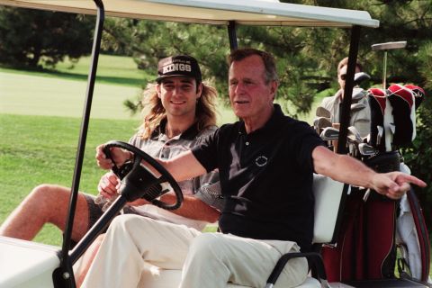 Bush plays golf with tennis player Andre Agassi in 1991.
