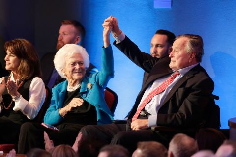 Bush holds up his wife's hand at a Republican presidential debate in 2016. One of their sons, former Florida Gov. Jeb Bush, was among the candidates in the debate.