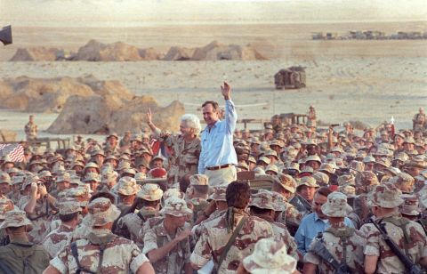 Bush and the first lady wave goodbye to US Marines and British troops after a Thanksgiving Day visit to Saudi Arabia in 1990.